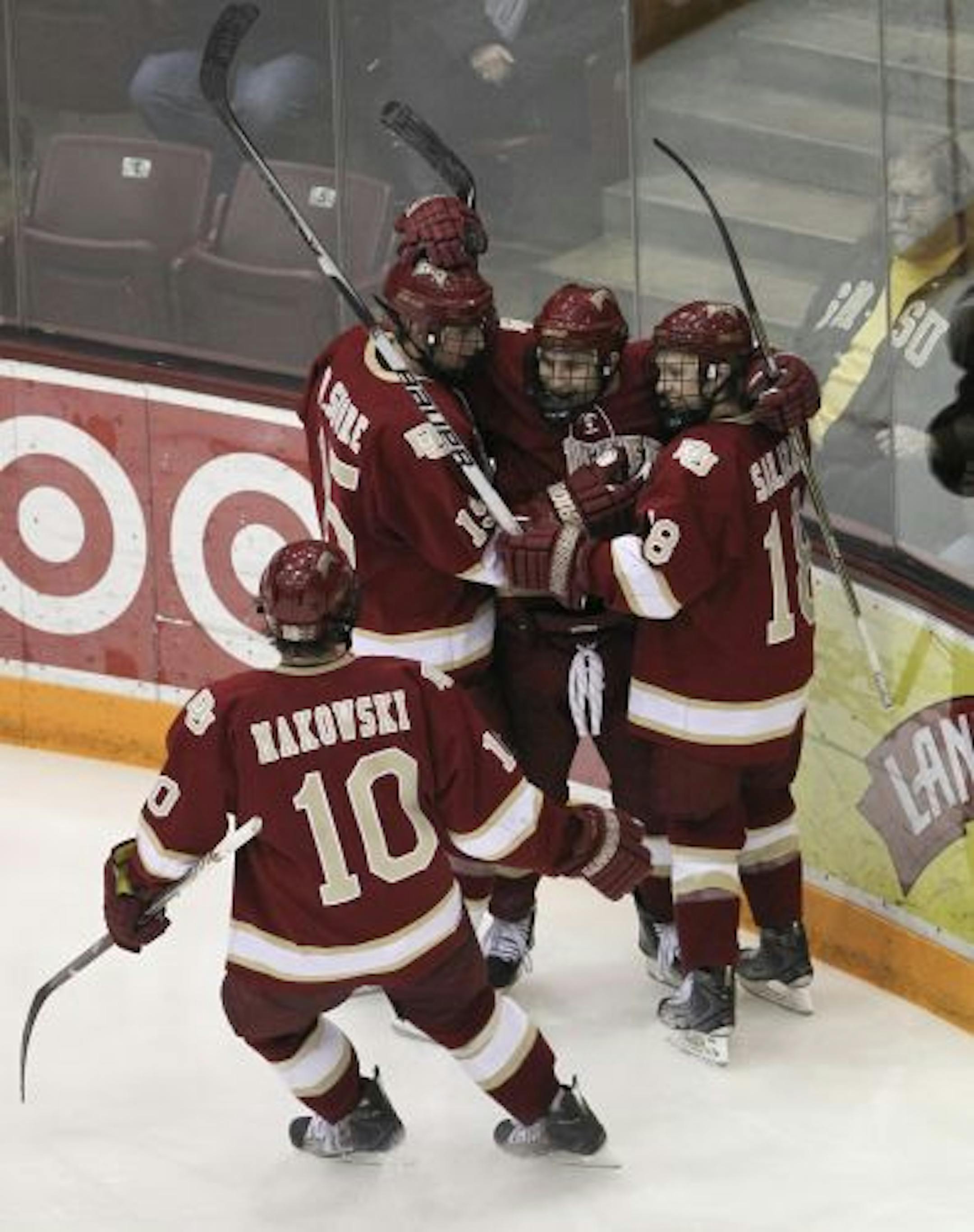 The Pioneers' Jason Zucker was congratulated by teammates Drew Shore, left, and Luke Salazar as David Makowski skated up to join them after Zucker scored the game winner in the third period Friday night against the Gophers.