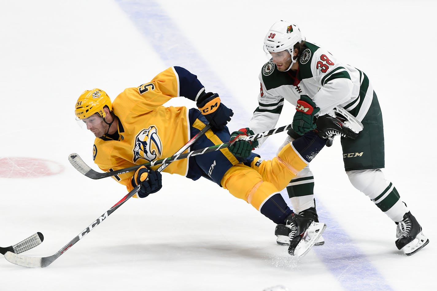 Predators left winger Austin Watson passed the puck just as he was taken down by Wild right winger Ryan Hartman (38) in an Oct. 2019 game. The two teams meet tonight at Xcel Energy Center.