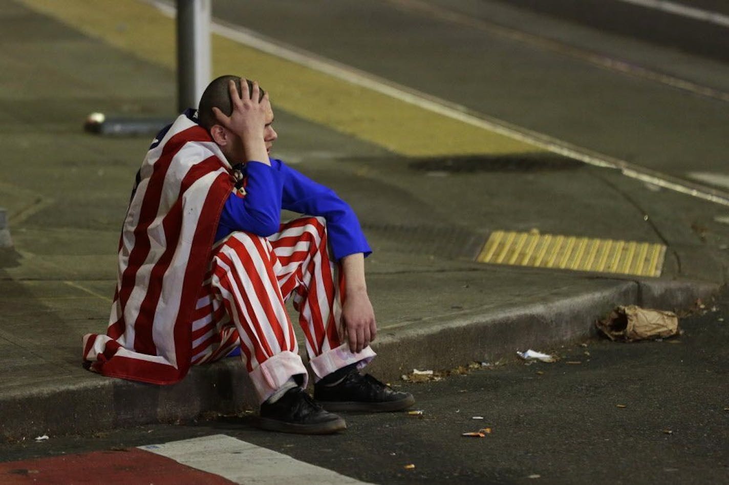 A man dressed in red-white-and-blue sits on the curb during a protest against President-elect Donald Trump, Wednesday, Nov. 9, 2016, in Seattle's Capitol Hill neighborhood.