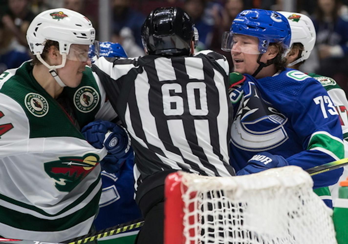 Minnesota Wild's Joel Eriksson Ek, left, of Sweden, and Vancouver Canucks' Tyler Toffoli, right, are separated by linesman Libor Suchanek during the first period of an NHL hockey game Wednesday, Feb. 19, 2020, in Vancouver, British Columbia. (Darryl Dyck/The Canadian Press via AP)