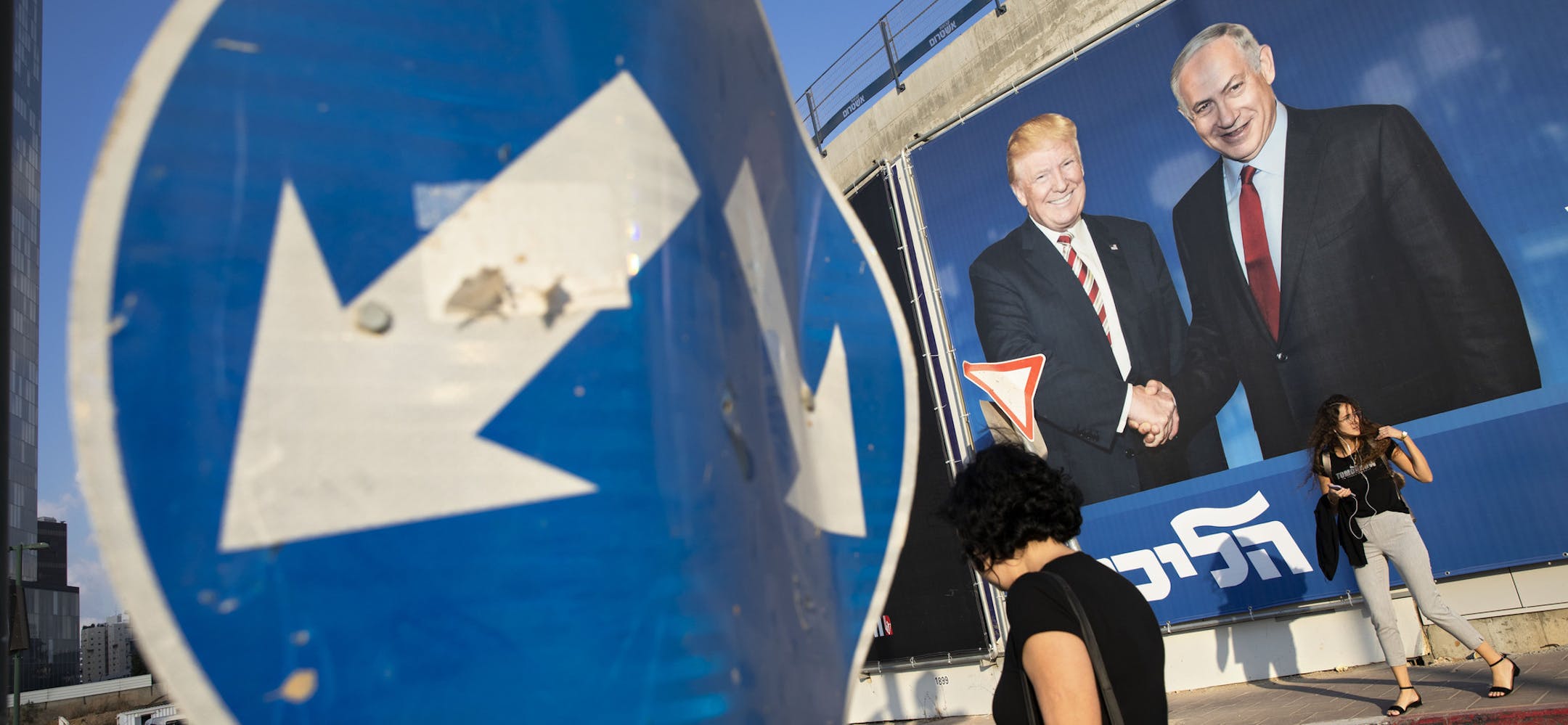People walk by an election campaign billboard for the Likud party that shows Israeli Prime Minister Benjamin Netanyahu, right, and US President Donald Trump, in Tel Aviv, Israel, Sunday, Sept 15, 2019. National elections are on Tuesday. (AP Photo/Oded Balilty)