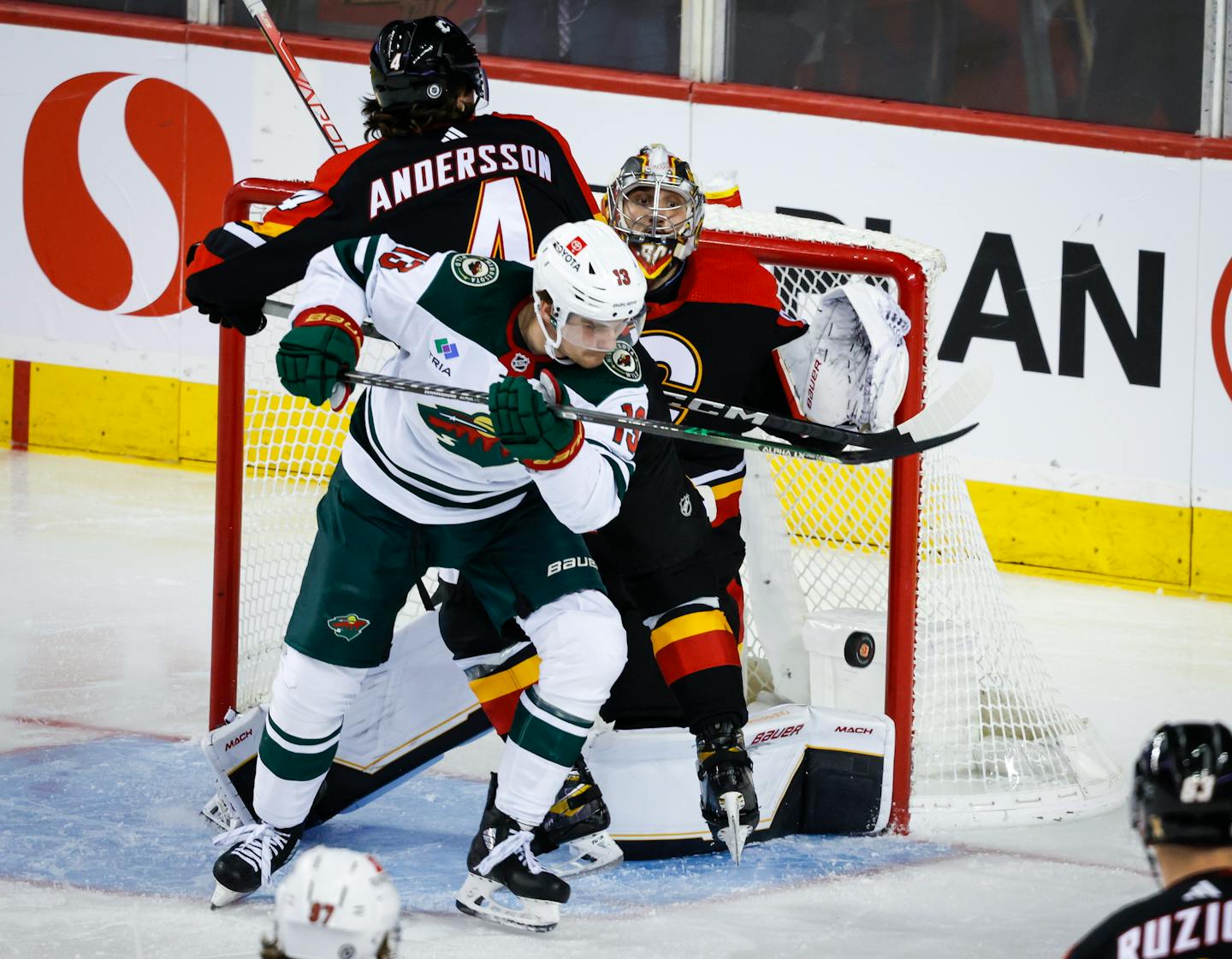 Minnesota Wild forward Sam Steel, center, checks Calgary Flames defenseman Rasmus Andersson, left, into goalie Dan Vladar during the third period of an NHL hockey game in Calgary, Alberta, Wednesday, Dec. 7, 2022. (Jeff McIntosh/The Canadian Press via AP)