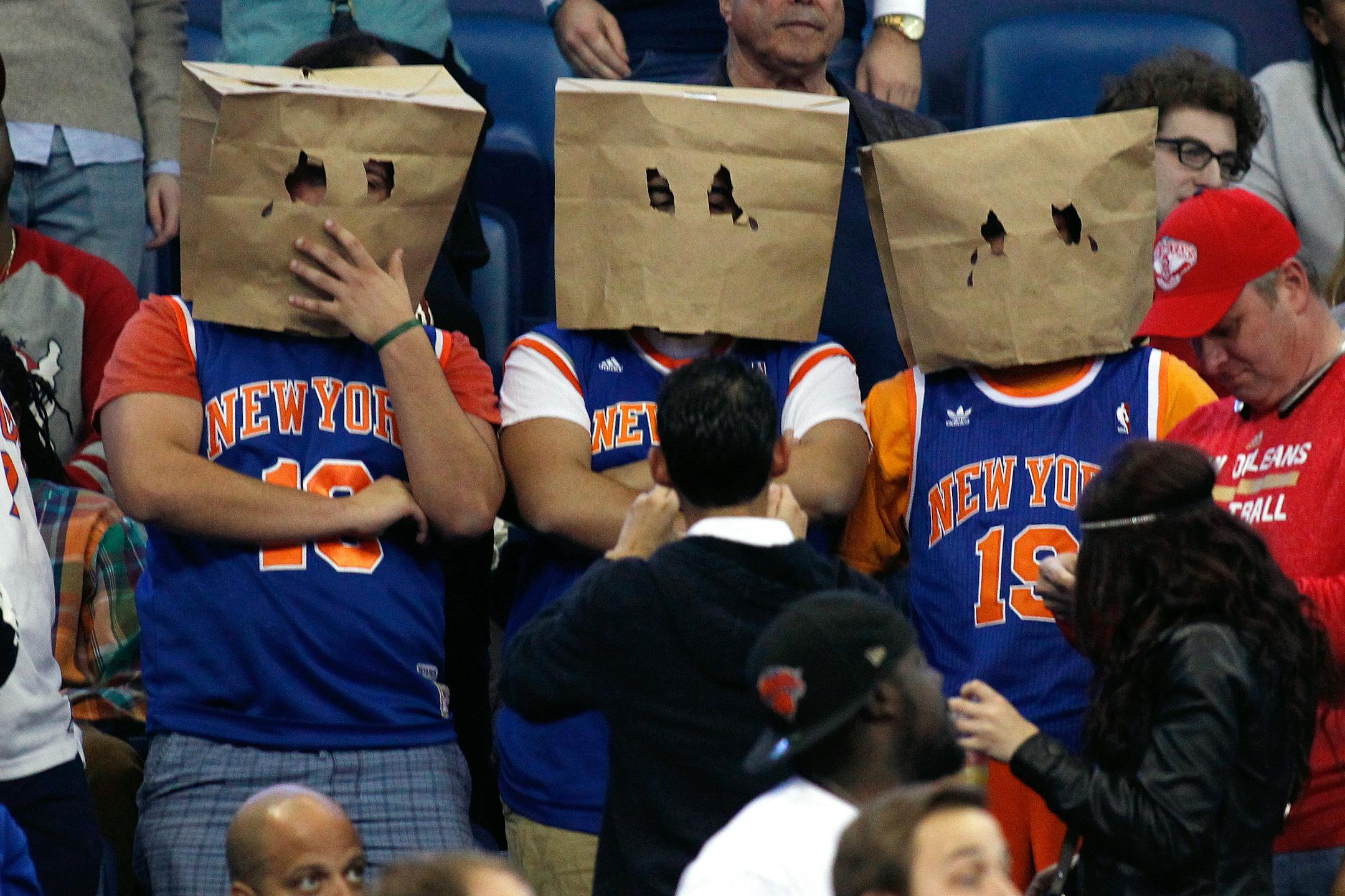 New York Knicks' fans stand during the second half of an NBA basketball game against the New Orleans Pelicans in New Orleans, Tuesday, Dec. 9, 2014. No team has more losses than the Knicks. Only Detroit has as many. Some fans in Knicks jerseys wore brown paper grocery bags over their heads, as fans of the �Aints� once did in the Superdome next door when the Saints were at their worst. (AP Photo/Jonathan Bachman)