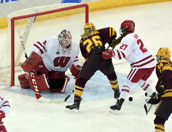 Wisconsin goaltender Kristen Campbell (35) knocks the puck away after a shot on goal by Minnesota's Sarah Potomak (26) during the third period in the 