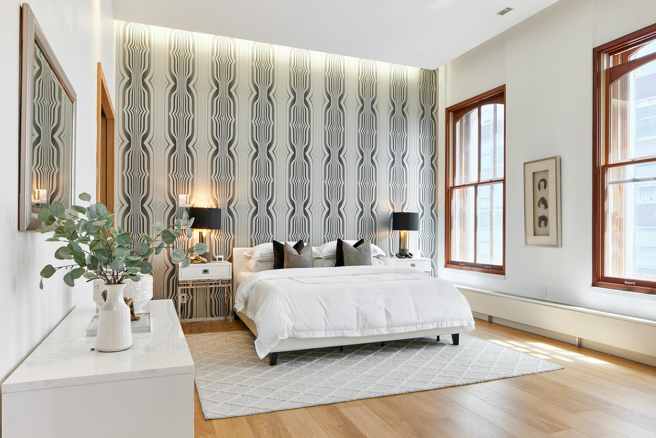 Vertical striped wallpaper one wall behind a headboard.