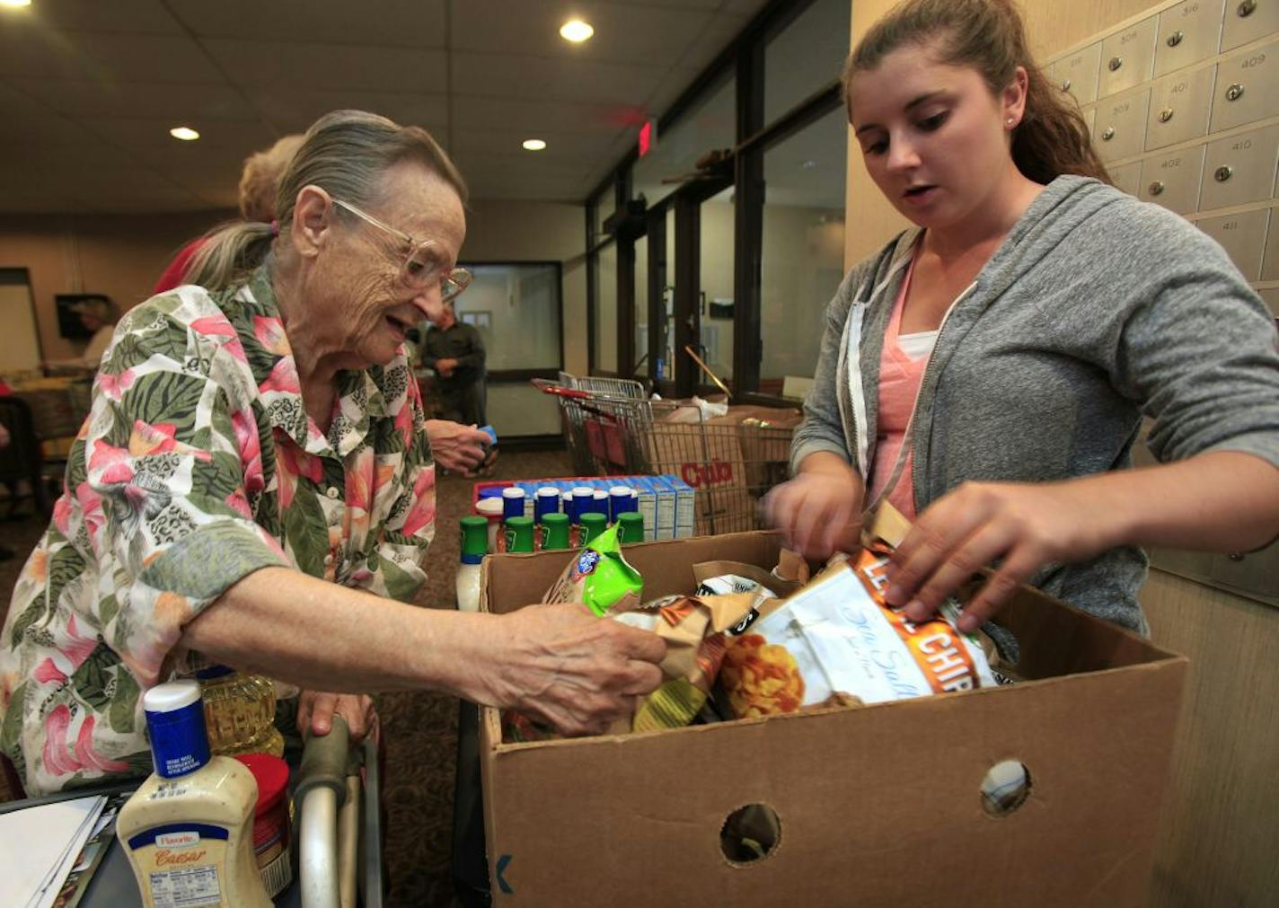 Volunteer Emma Grund, right, helped Patricia Hopkins pick out food brought to Hopkins Village Apartments by the ICA food shelf.