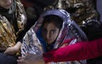 A Iraqi girl looks on as she is covered with a thermal blanket after she and other migrants and refugees were rescued by the Greek coast guard, early 