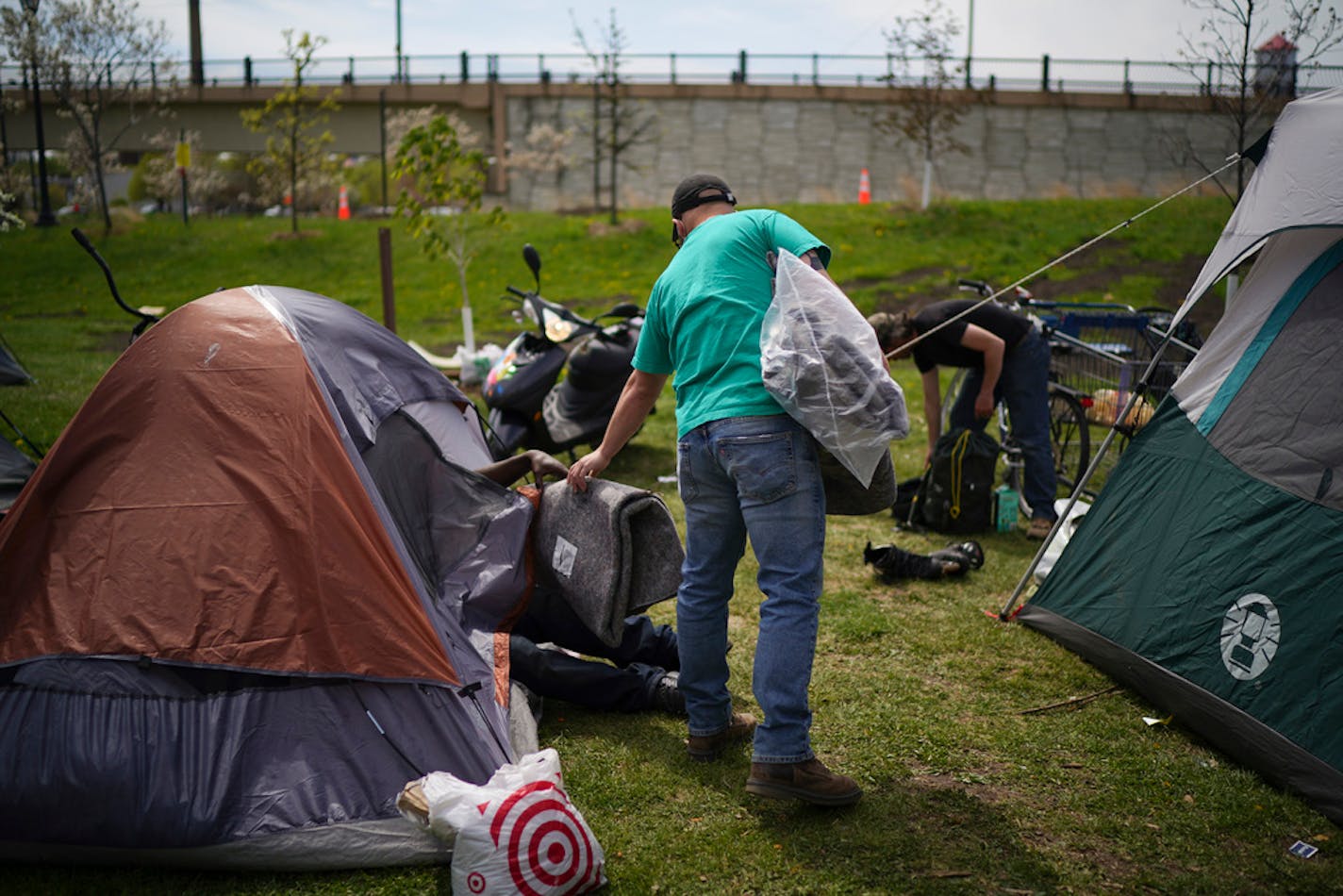 Chris Knutson handed a blanket to resident of the encampment near the Sabo bridge during an outreach visit Thursday afternoon. ] JEFF WHEELER • Jeff.Wheeler@startribune.com