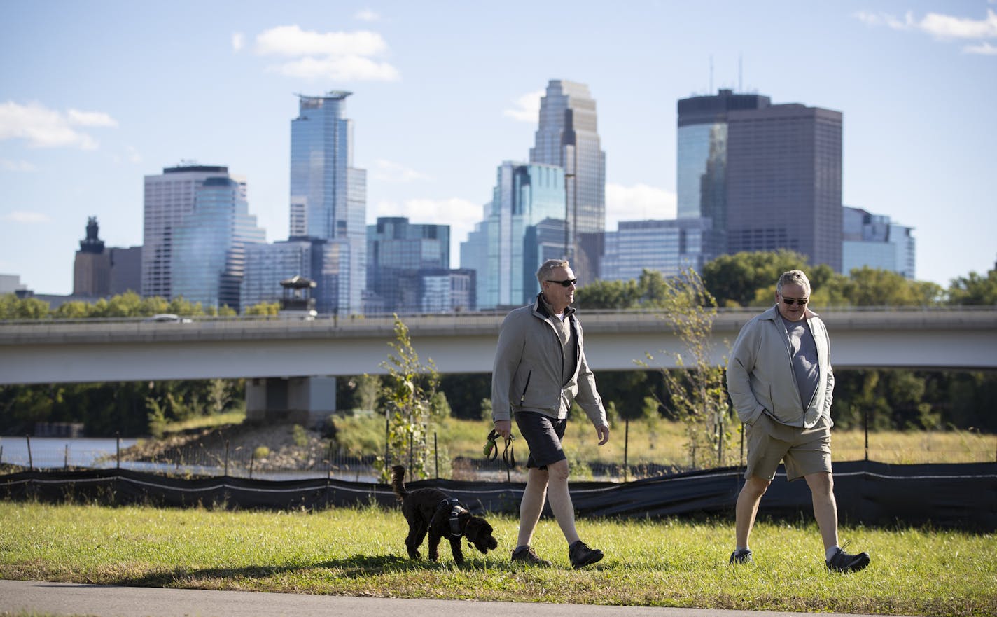 Jay Meekin and Steve Golat walked their dog Duffy on a walking path in the future home of a park next to the Graco factory with a view of downtown. The Minneapolis Park Board says it has reached a settlement with Graco Minnesota Inc. over an easement on riverside property owned by Graco. Photographed in Minneapolis, Minn., on Friday, September 28, 2018. ] RENEE JONES SCHNEIDER &#x2022; renee.jones@startribune.com