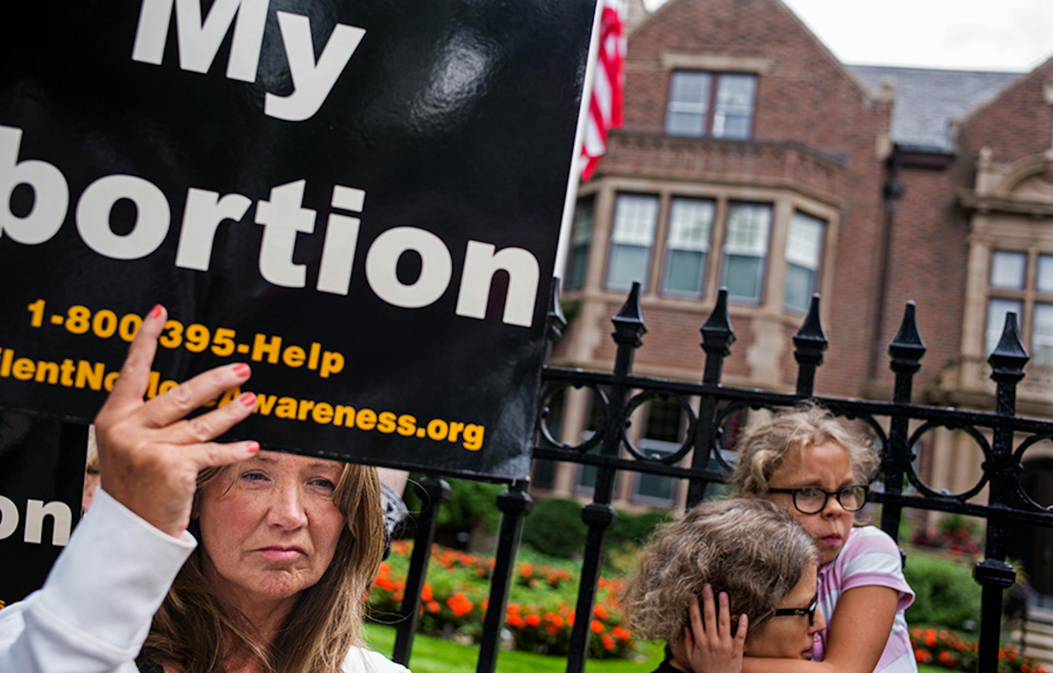 In front of the governor's mansion in St. Paul, pro-life activists gathered to ask Gov. Mark Dayton to investigate Planned Parenthood and calling for legislators to defund the organization. Ann Marie Cosgrove, left, held a sign "I Regret My Abortion" in front of the gate. She says all abortion clinics need to be investigated.
