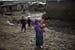 An Afghan refugee girl carries her younger brother as she walks with bare feet on slippery ground of a slum following rainfall on the outskirts of Isl