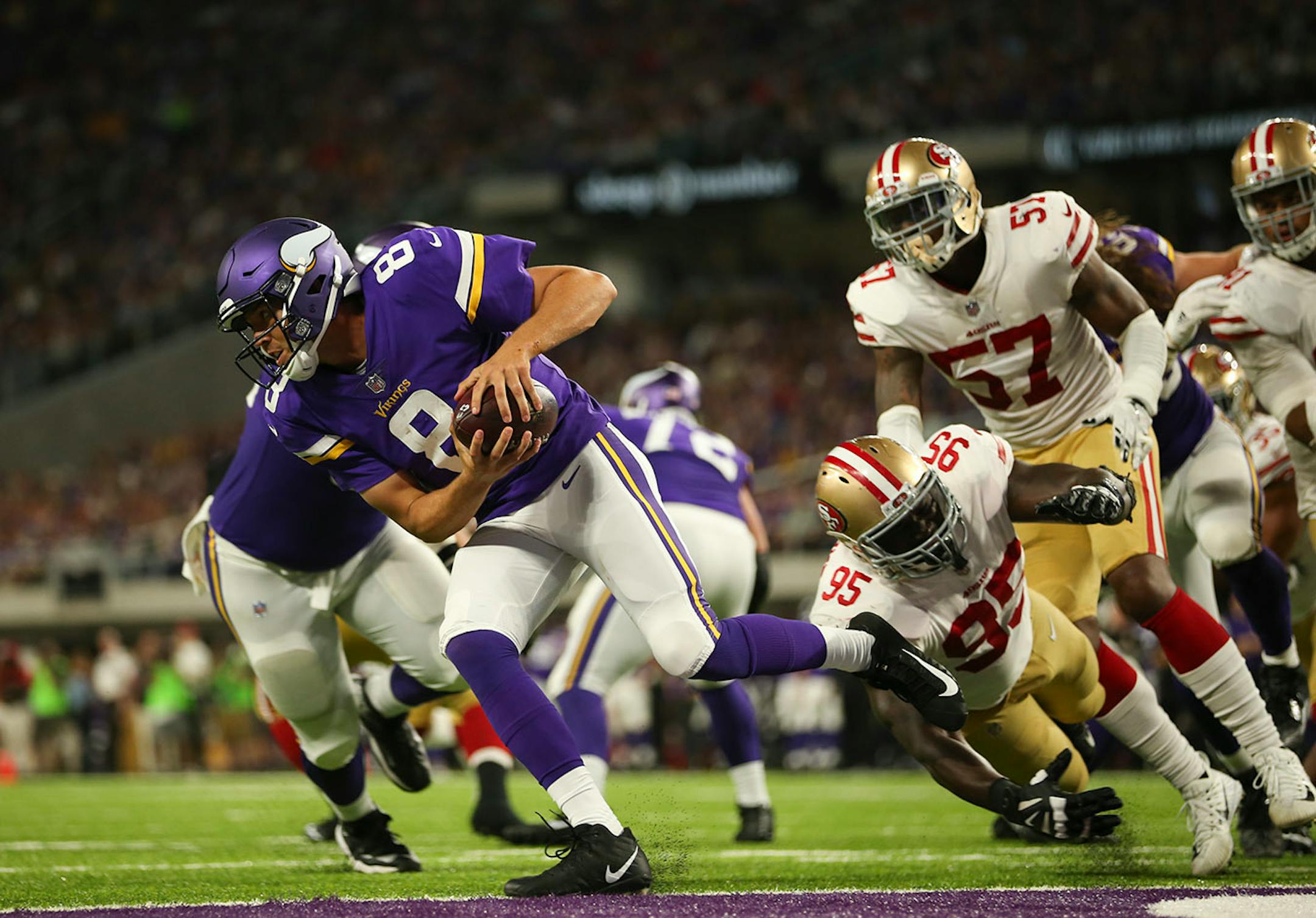 Minnesota Vikings quarterback Sam Bradford (8) scrambled out of the pocket to elude 49ers defensive end Tank Carradine (95) and outside linebacker Eli Harold (57) in the second quarter.