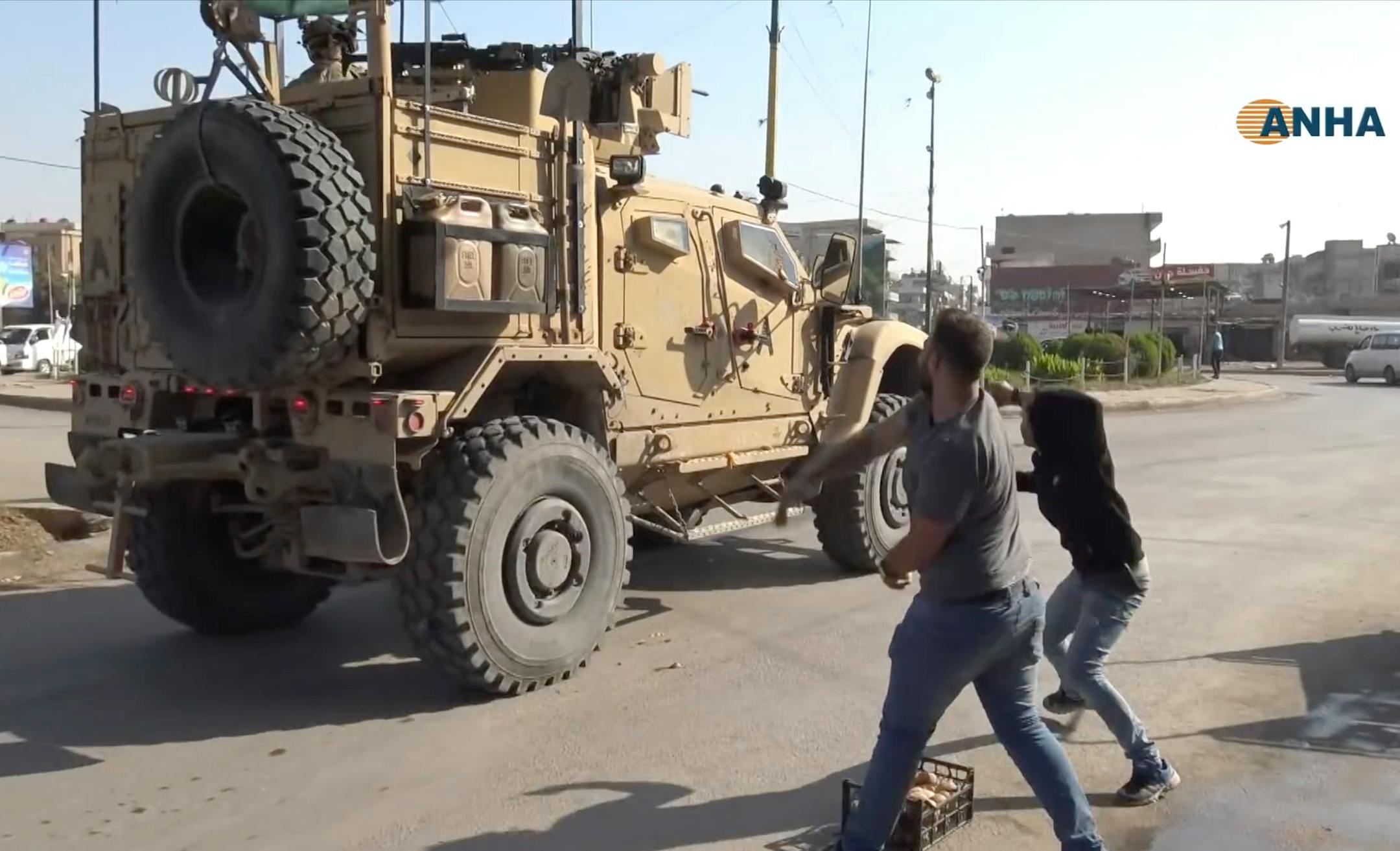 In this frame grab from video provided by Hawar News, ANHA, the Kurdish news agency, residents who were angry over a U.S. withdrawal from Syria hurled potatoes at American military vehicles in the town of Qamishli, northern Syria, on Monday, Oct. 21, 2019.