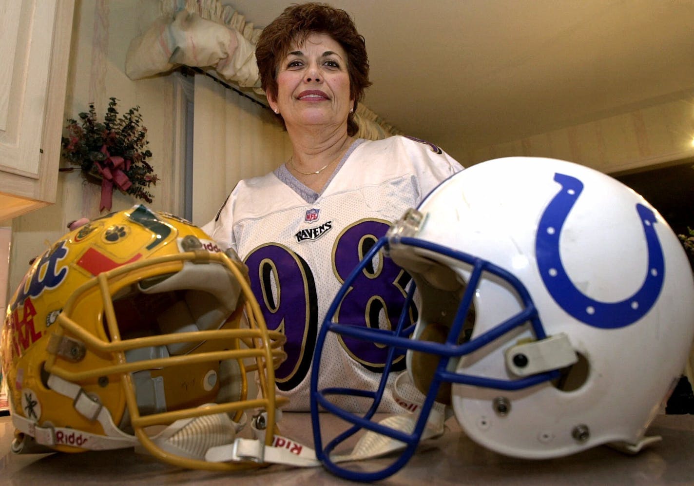 Rosemarie Siragusa, mother of Baltimore Revens 340-pound tackle Tony "The Goose" Siragusa, poses in his Pitt and Colts helmets at her home in Kenilworth, N.J., Friday, Jan. 19, 2001. (AP Photo/Mike Derer)