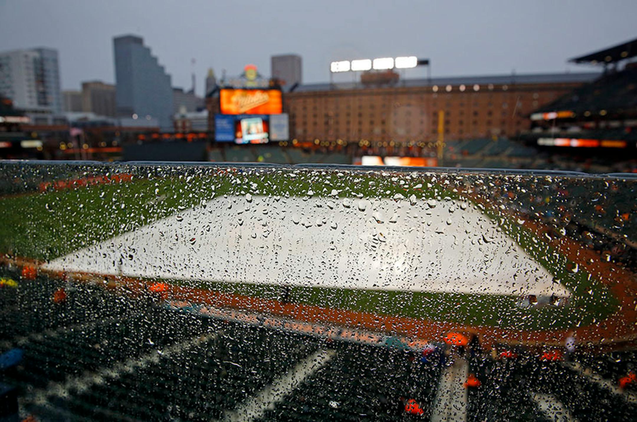 Raindrops coated a pane of glass above a tarp-covered infield during a rain delay in an Opening Day game between the Orioles and the Twins in Baltimore on Monday.