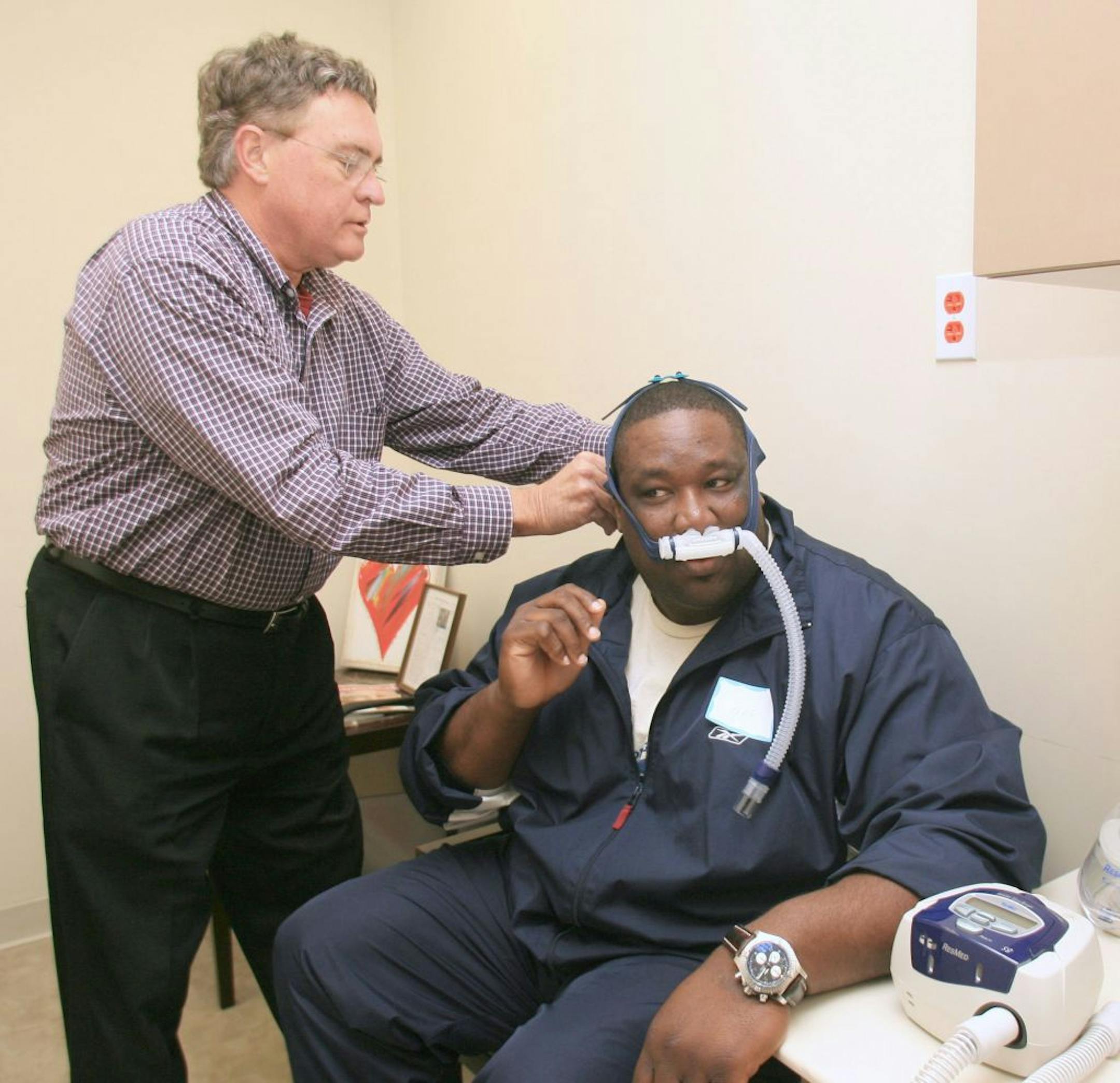 In this 2007 photo, sleep technical Bob Redington, left, helps former Miami Dolphins player Keith Sims put on a Continuous Positive Airway Press Machine at the Living Heart NFL Players CV Health Programin Miami.