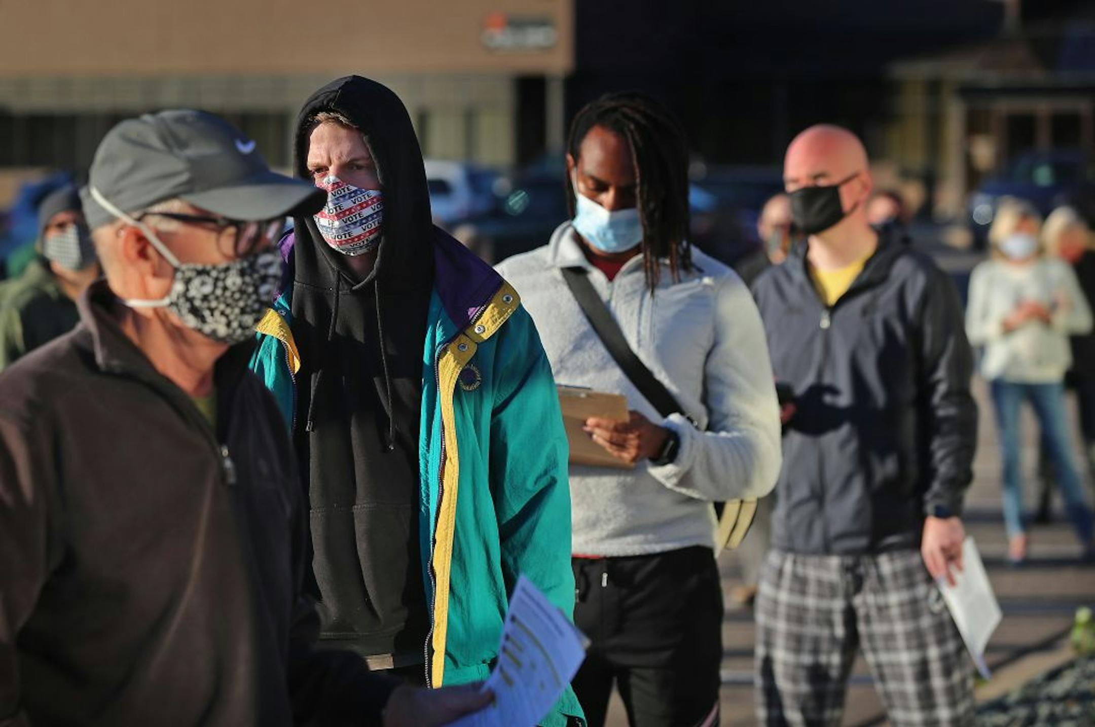 Jack O'Rourke of Minneapolis, whose mother made him a custom mask urging people to vote, joined other voters during early voting at Minneapolis Elections and Voter Services Friday in Minneapolis. O'Rourke said he is looking "at the state of the country," in the pandemic and believes the U.S. is far worse off than other developed nations and that is what he said he will base his vote on.