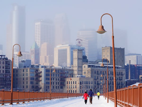 The Minneapolis skyline is locked in an icy shroud Friday in Minneapolis, seen from the Stone Arch Bridge. ]