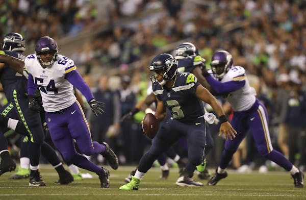 Seattle Seahawks quarterback Russell Wilson (3) turned to run the other way when Vikings offensive guard Willie Beavers (64) broke though the Seahawks