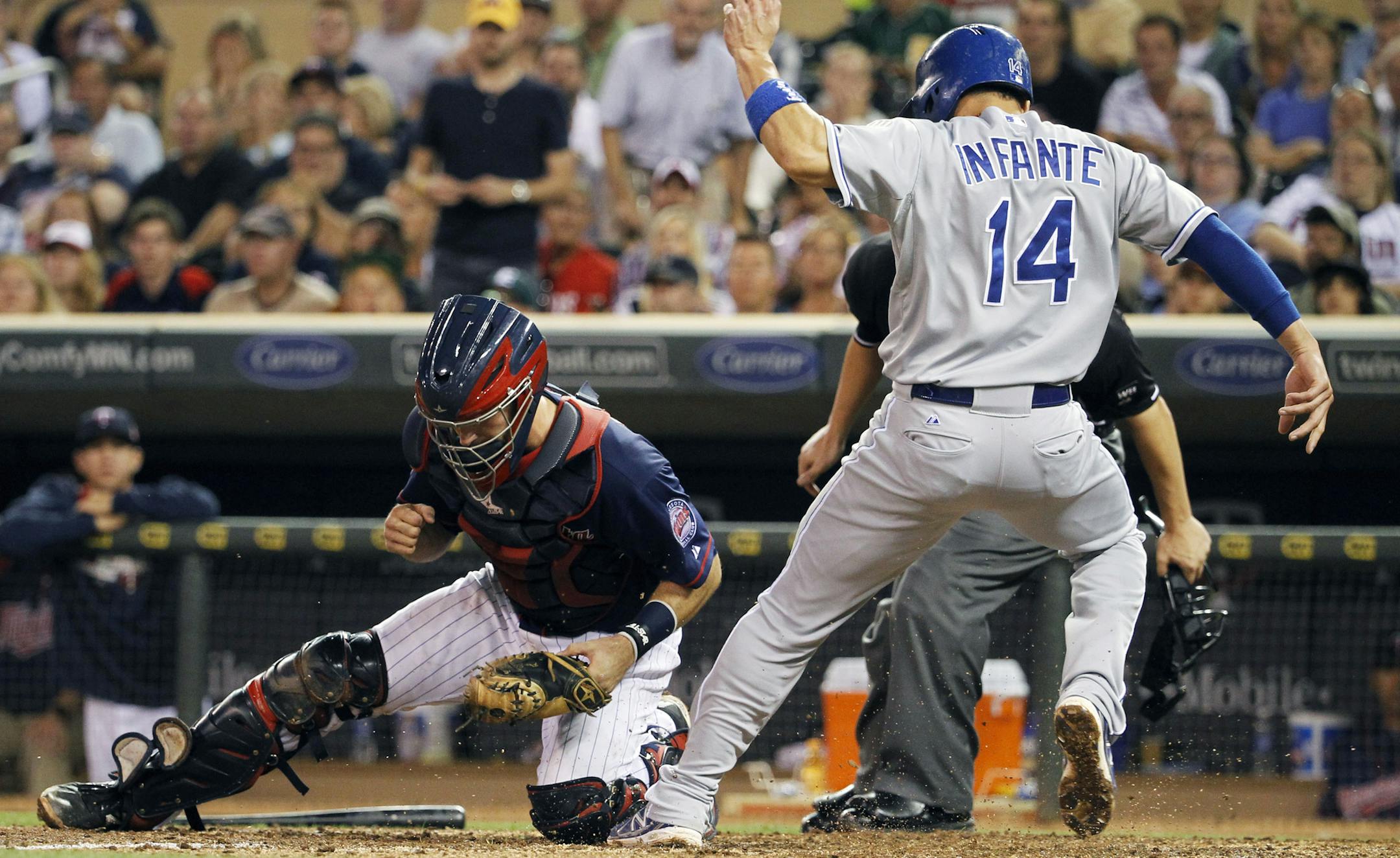 Kansas City Royals' Omar Infante (14) scores on a single by Billy Butler as Minnesota Twins catcher Eric Fryer, left, drops the throw from center during the fifth inning of a baseball game in Minneapolis, Monday, Aug. 18, 2014. (AP Photo/Ann Heisenfelt)