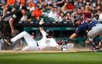 The Tigers' Nicholas Castellanos slides safely into home plate under the tag of Twins catcher Jason Castro in the fifth inning