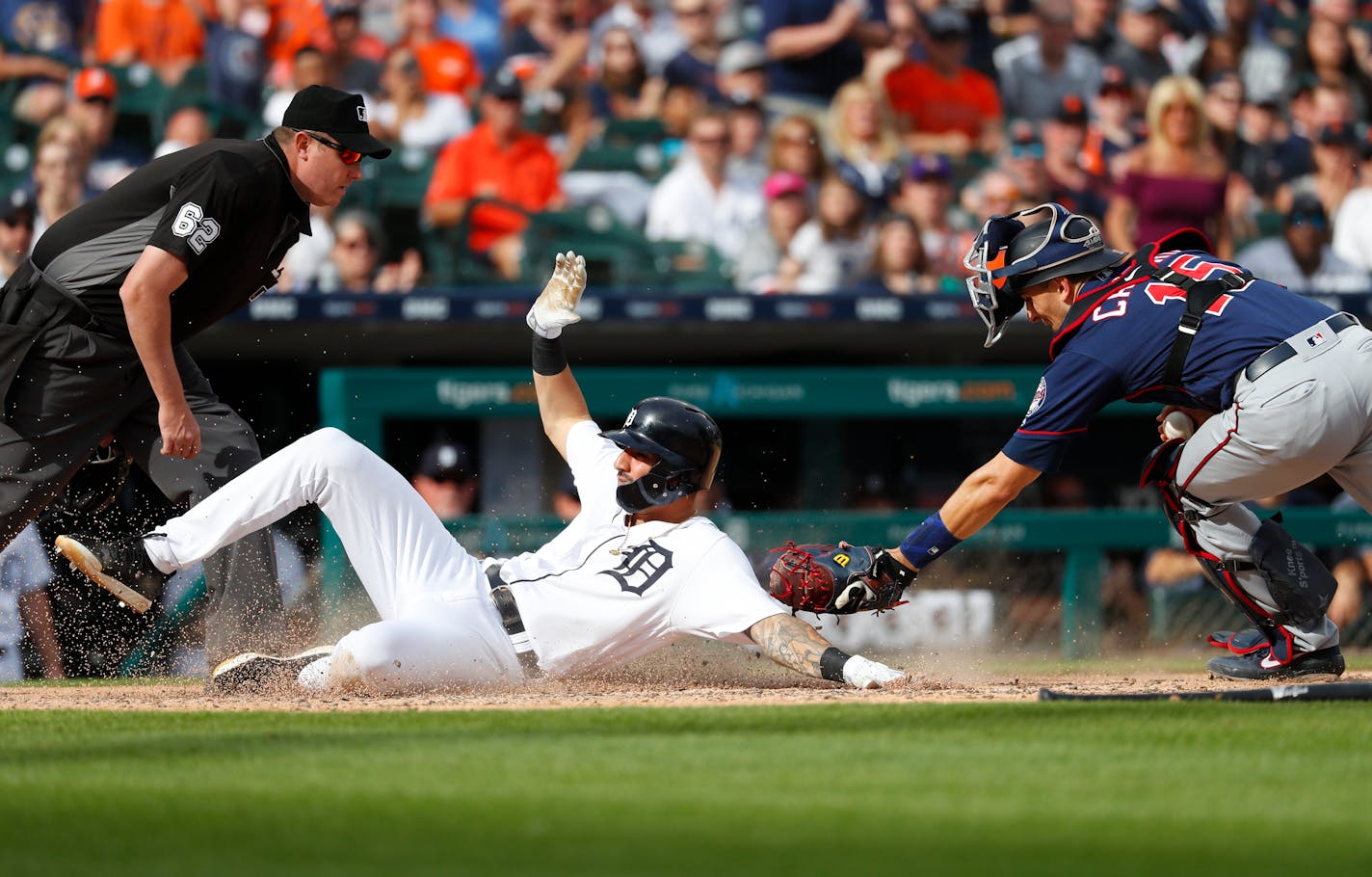 The Tigers' Nicholas Castellanos slides safely into home plate under the tag of Twins catcher Jason Castro in the fifth inning