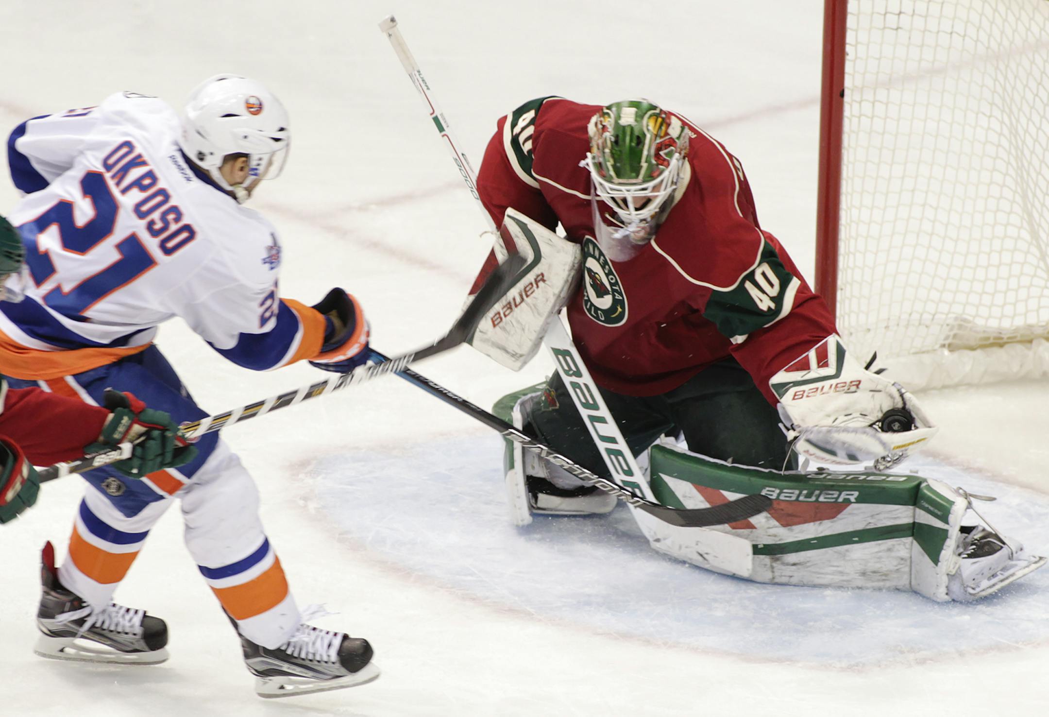 Minnesota Wild goalie Devan Dubnyk (40) makes a save on New York Islanders right wing Kyle Okposo (21) as Minnesota Wild defenseman Mike Reilly (4) defends during the third period of an NHL hockey game, Tuesday, Feb. 23, 2016, in St. Paul, Minn. Dubnyk had 27 saves on the night as the Islanders won 4-1. (AP Photo/Paul Battaglia)