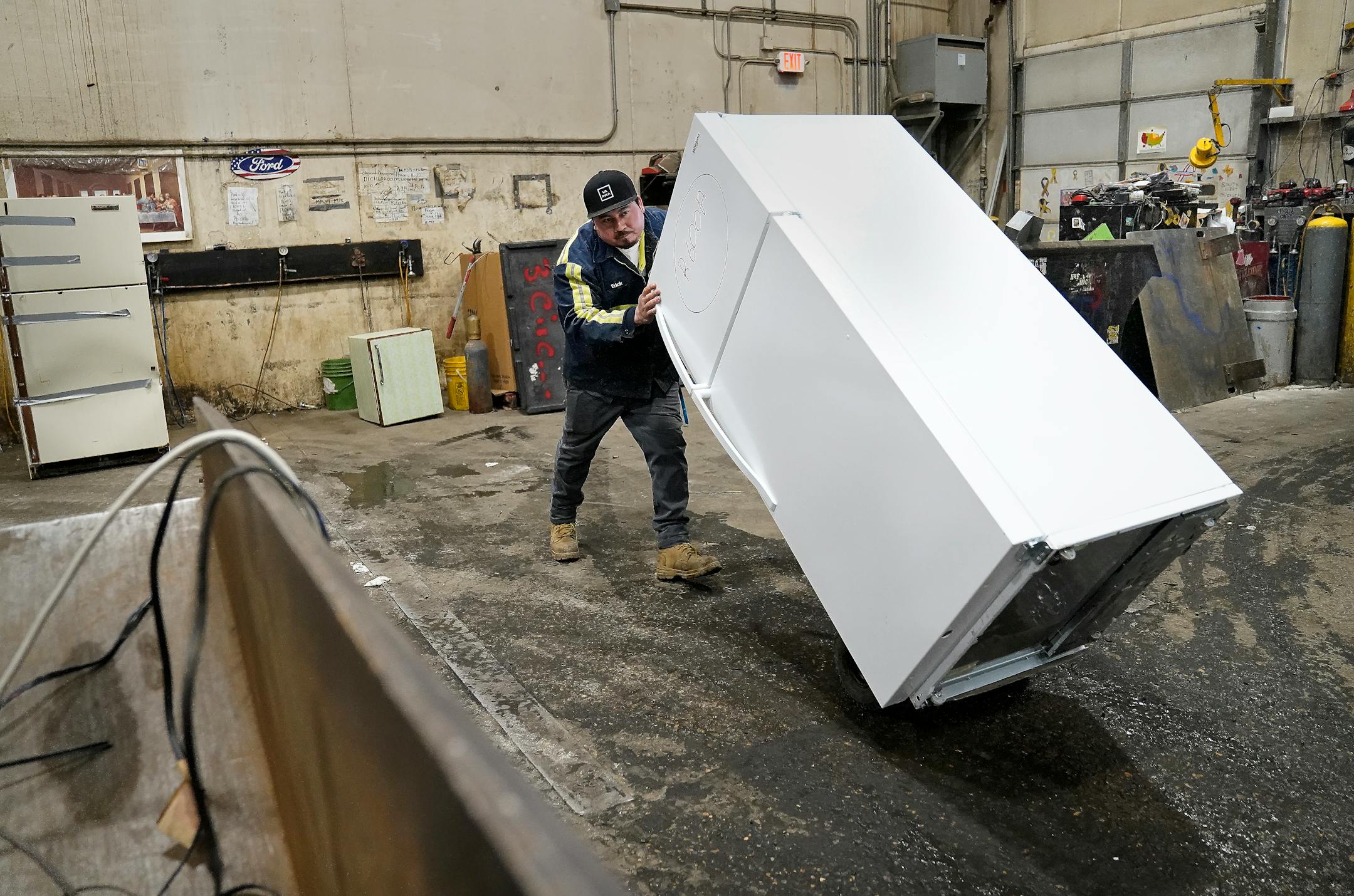 J.R.'s Advanced Recyclers dock supervisor Erick Perez moves an old refrigerator for recycling with a hydroflurocarbon-based refrigerant inside that will be removed of the climate-polluting refrigerant at the recycler.
