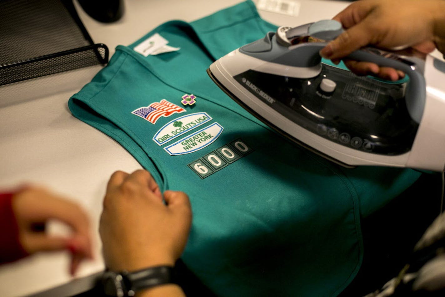 Giselle Burgess, leader of Troop 6000, irons patches on a vest at the Girl Scouts of Greater New York headquarters in New York, April 13, 2017. Girl Scout Troop 6000, serving homeless families placed by the city on 10 floors of a Sleep Inn in Queens, is the first in New York City designated solely for homeless girls. (Sam Hodgson/The New York Times)