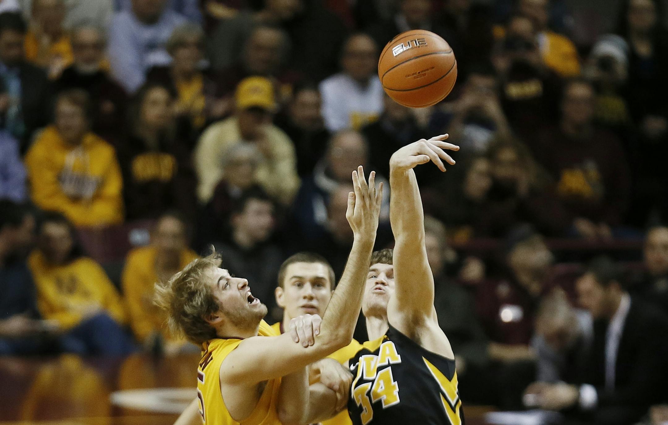 Iowa Hawkeyes center Adam Woodbury (34) tipped the ball away from Minnesota Gophers center Elliott Eliason (55) at tip off Tuesday at Williams arena January 13, 2015 Minneapolis, MN.