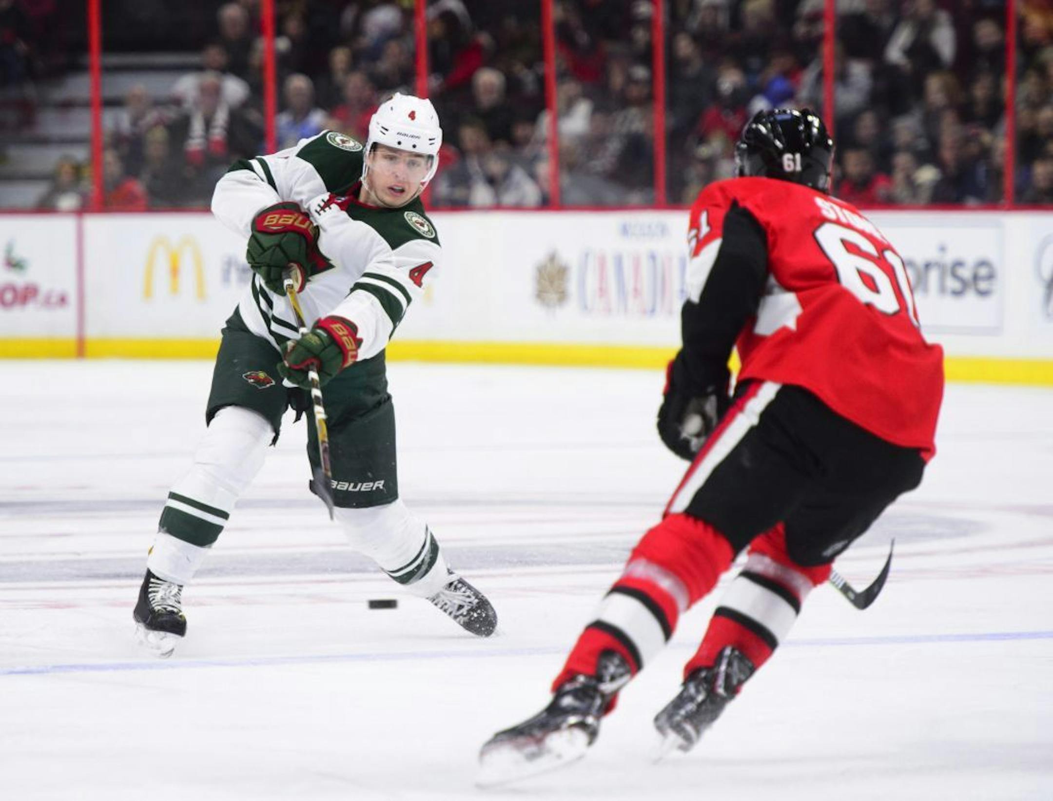 Minnesota Wild's Mike Reilly dumps the puck past Ottawa Senators' Mark Stone during third period NHL hockey action in Ottawa on Tuesday, Dec. 19, 2017.