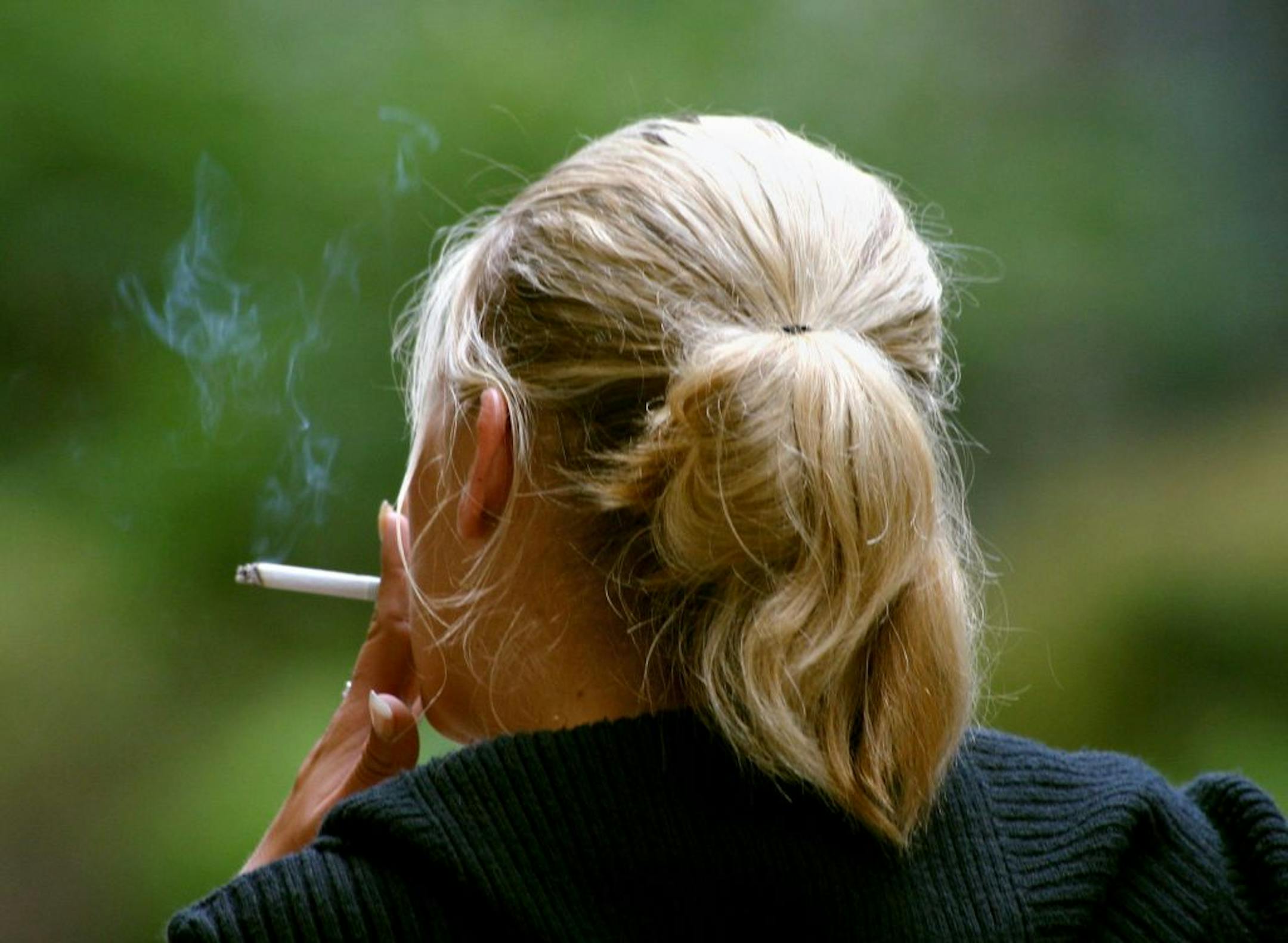 FILE - In this July 20, 2006 file photo, a woman smokes a cigarette during a break from work in downtown Chicago. New research published in the New England Journal of Medicine's issue coming out Thursday, Jan. 24, 2013, finds that women who smoke today have a much greater risk of dying from lung cancer than they did decades ago compared to those who never smoked. That is partly because they are starting younger and smoking more than women used to.
