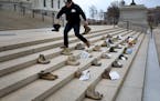 David Peters, a U.S. Marine from Stillwater who is part of Operation: 23 to 0, places the boots of soldiers felled by suicide on the steps outside of 