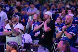 Cody Kraskey, Garret Wright, and Zac Evans, from left, react to the Vikings moving up to the 17th pick and selecting outside linebacker Dallas Turner 