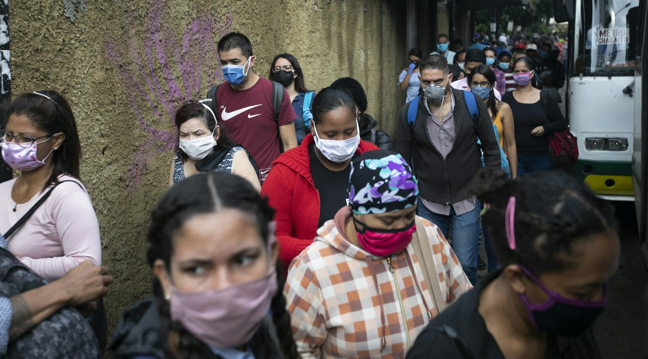 Pedestrians and commuters wearing face masks amid the new coronavirus pandemic crowd a sidewalk near a bus stop in Caracas, Venezuela, Monday, June 1, 2020. After two and a half months of COVID-19 related quarantine, some industries are allowed to reactivate under a scheme of five days' work and 10 days rest. (AP Photo/Ariana Cubillos)