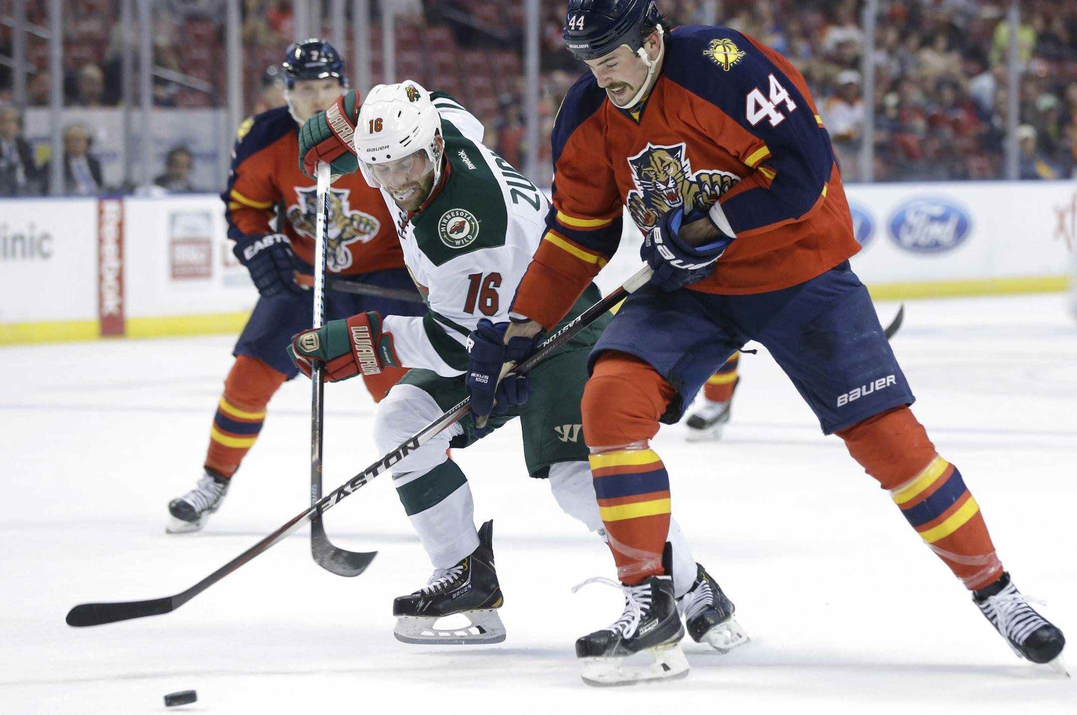 Minnesota Wild left wing Jason Zucker (16) and Florida Panthers defenseman Erik Gudbranson (44) go for the puck during the first period of an NHL hockey game, Monday, Nov. 24, 2014, in Sunrise, Fla.(AP Photo/Lynne Sladky)