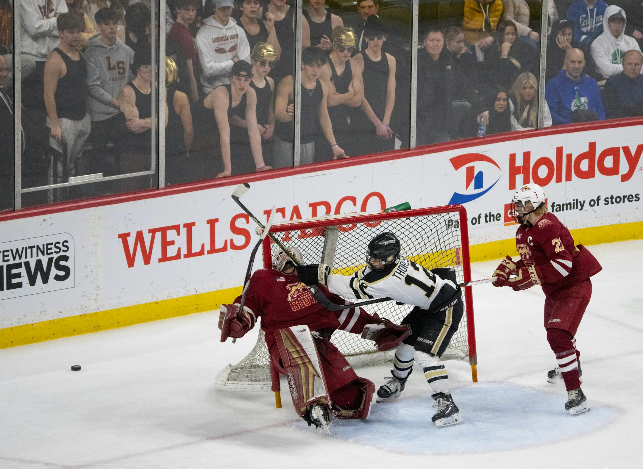 Andover Huskies forward Gavyn Thoreson (12) crashed into Lakeville South Cougars goaltender Jack Hochsprung (33) while he was defended by Lakeville South Cougars forward Ashton Dahms (22) in the first period.