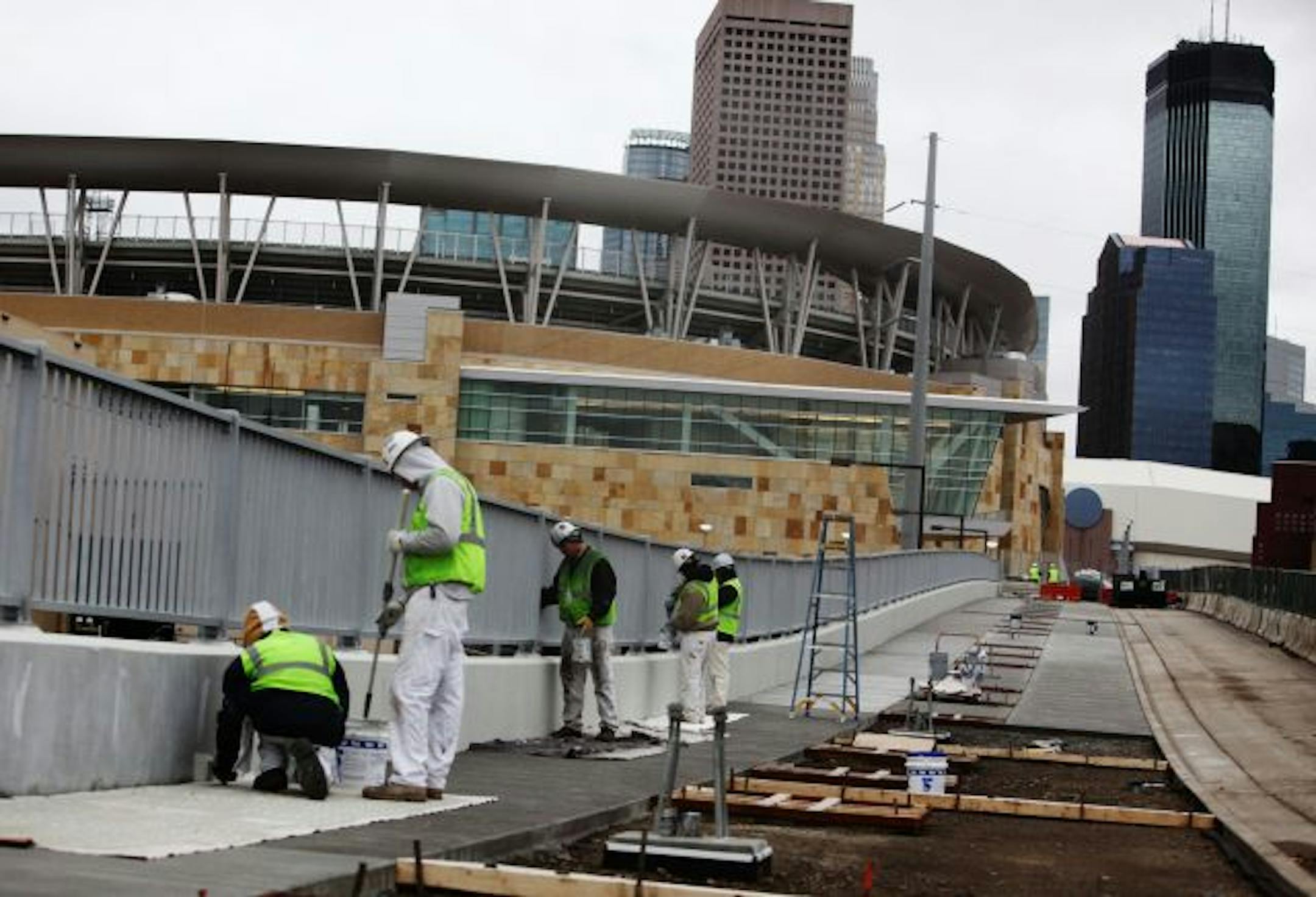 Workers painted a railing last week along a pedestrian walkway north of Target Field, one of the many exterior projects that crews are scrambling to finish. The improvements are part of an effort to extend downtown Minneapolis two blocks beyond Target Center, Ballpark Authority executive director Dan Kenney says.