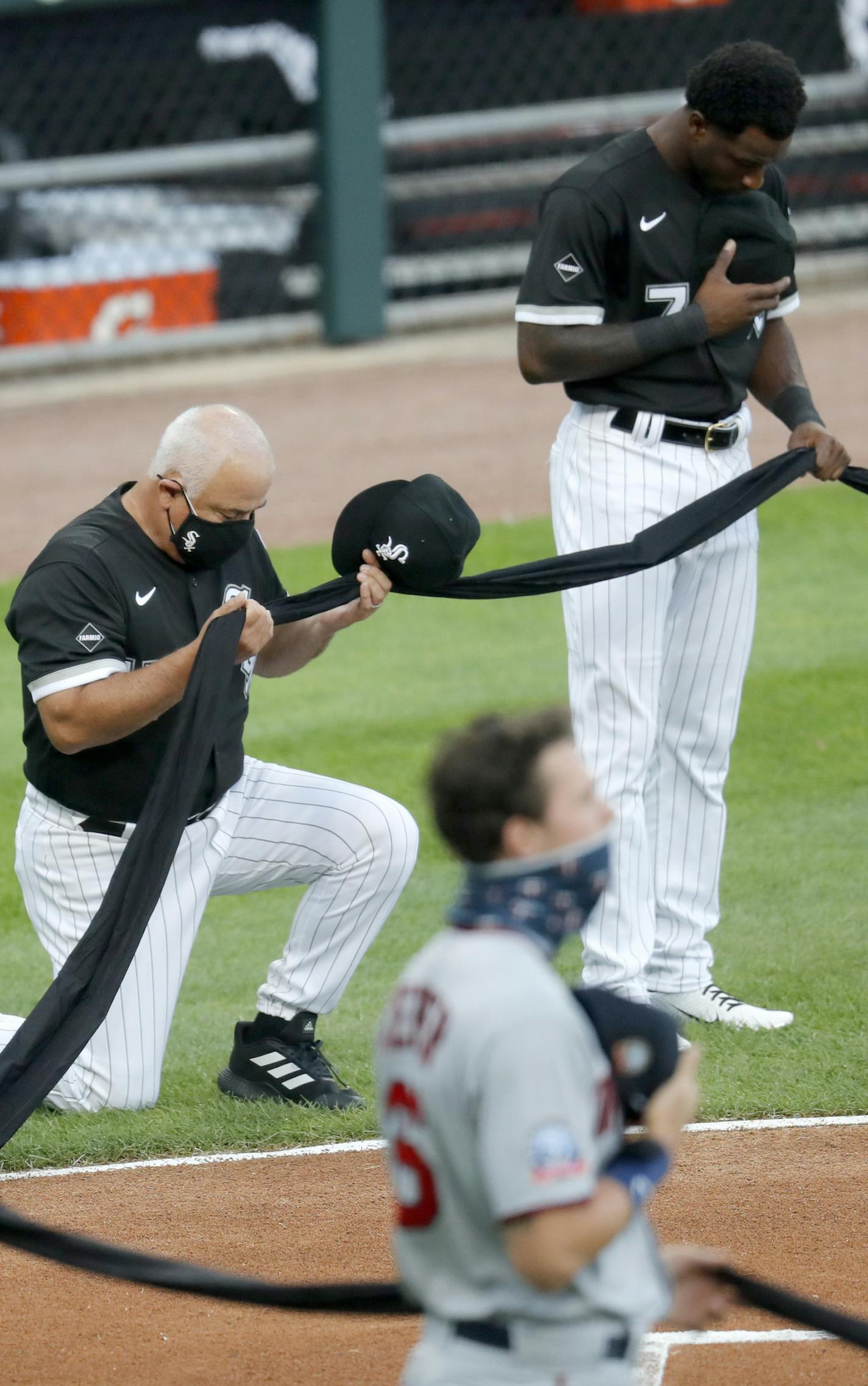 Chicago White Sox manager Ricky Renteria kneels for social justice next to Tim Anderson before a baseball game against the Minnesota Twins, Friday, July 24, 2020, in Chicago. (AP Photo/Charles Rex Arbogast)