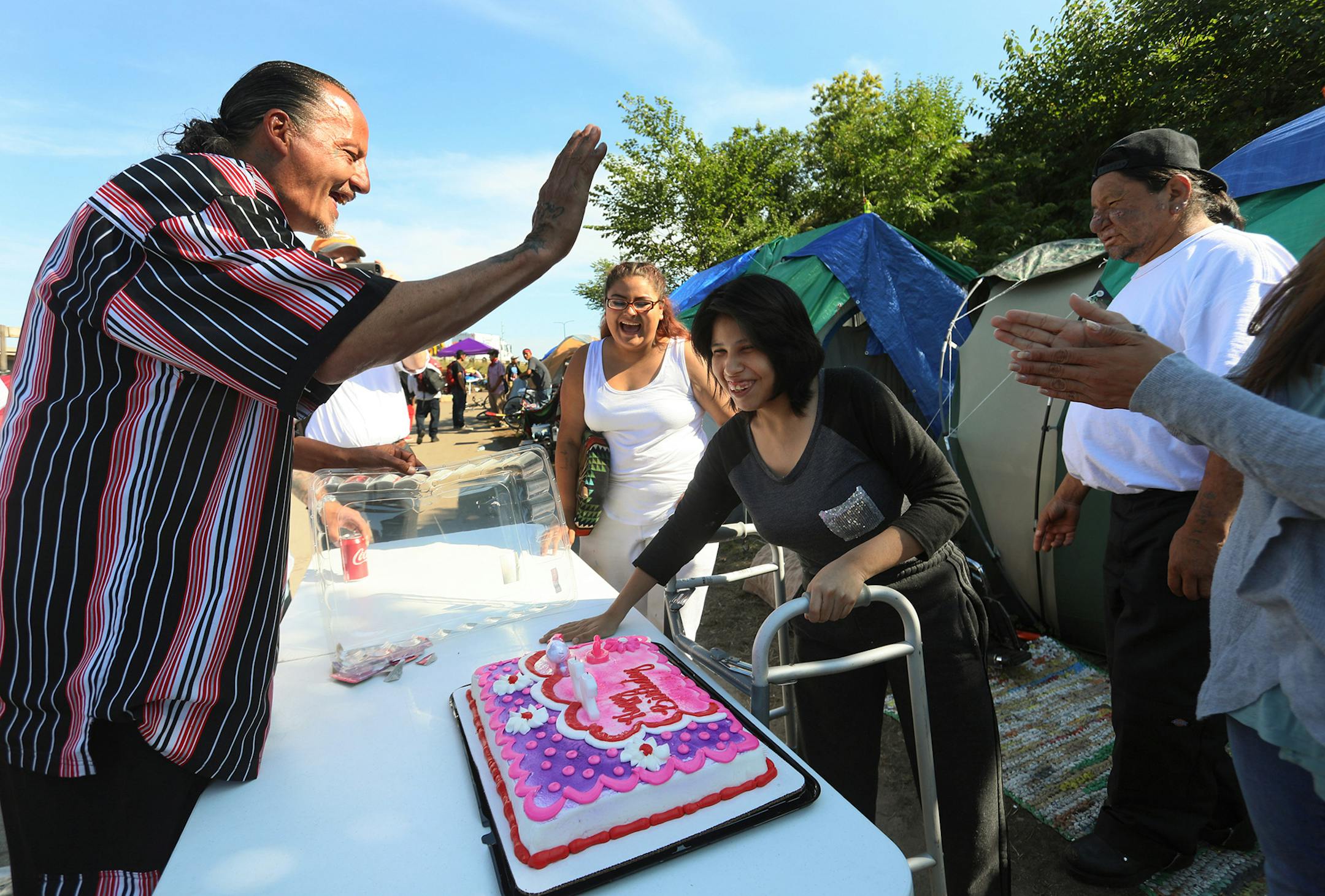 James Cross, the founder of the street outreach group Natives Against Heroin, spent nearly half of his life in prison for drug-related crimes but is working hard now to help people in his Native American community, particularly the poor and those with substance abuse problems. Here, Cross raised his hand to give a high five to birthday girl Jamie Threelegs, 27, during an impromptu birthday party organized by Cross and NAH in a growing homeless encampment Friday, Sept. 7, 2018 in south Minneapoli
