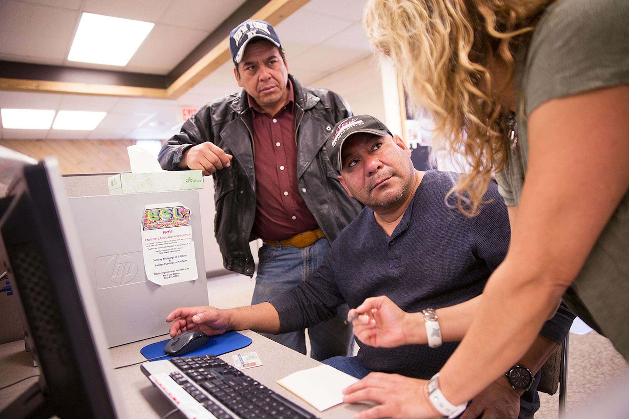 Jose Martinez, from left, and Ernesto Valle of Las Vegas, Nevada get help from June Hesser, a customer service representative at Job Service North Dakota in Williston, North Dakota on Tuesday, March 31, 2015. Martinez and Valle are seasonal construction workers who work in Las Vegas in the winter and come to Williston for work in the summer.