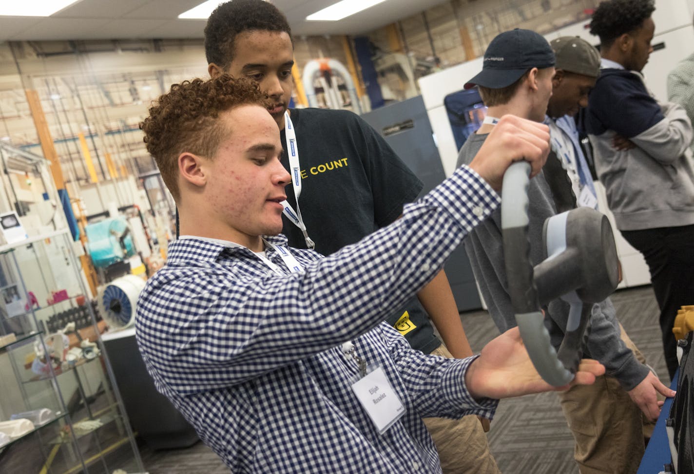 High school student Elijah Rosalez inspects a 3-D printed steering wheel, commenting on how heavy it is.