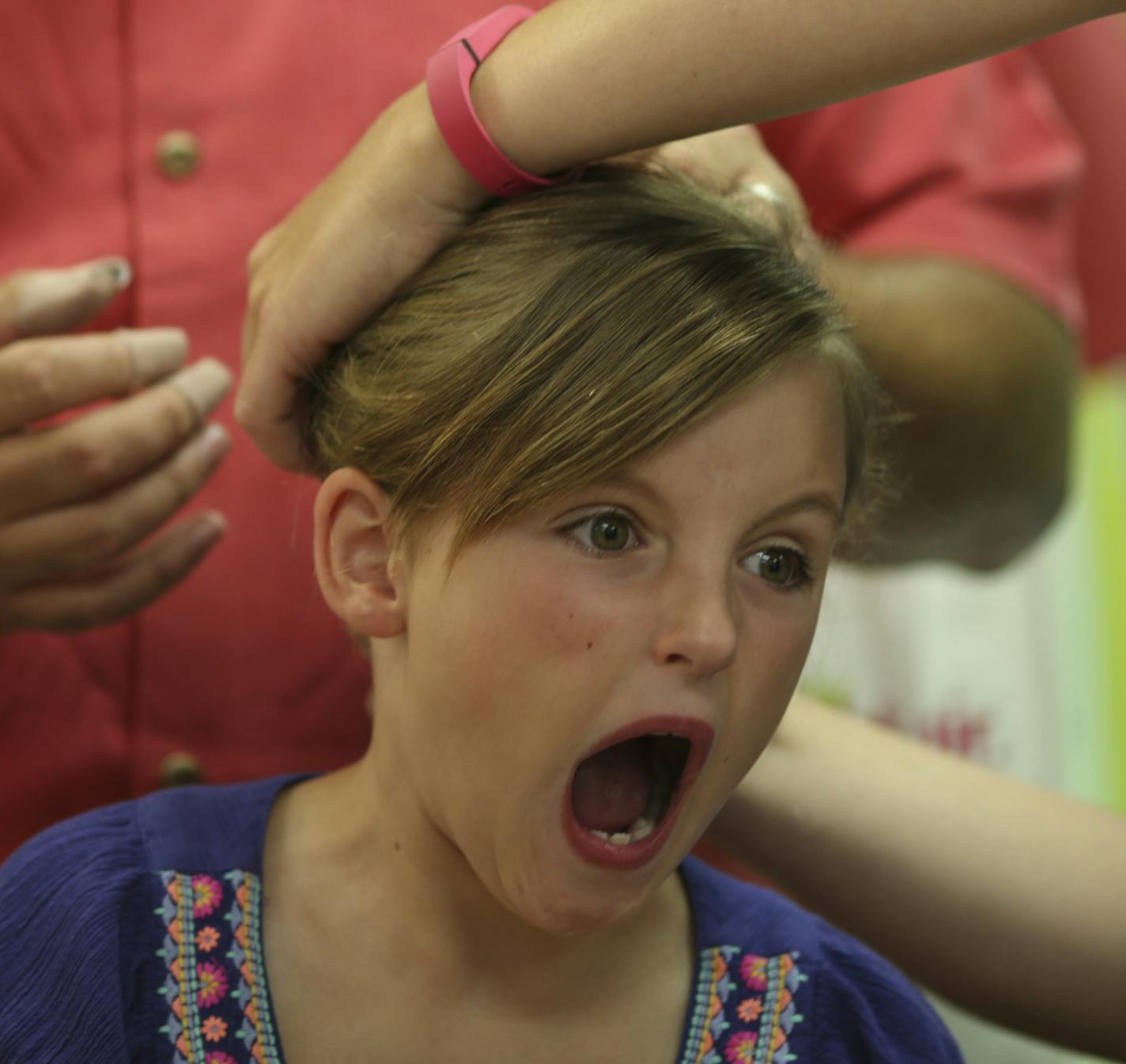 Sophia Korman, 7, reacted as a stylist helped her dad, Mike, fix her hair in a ponytail during the braiding class at Kids&#x2019; Hair.