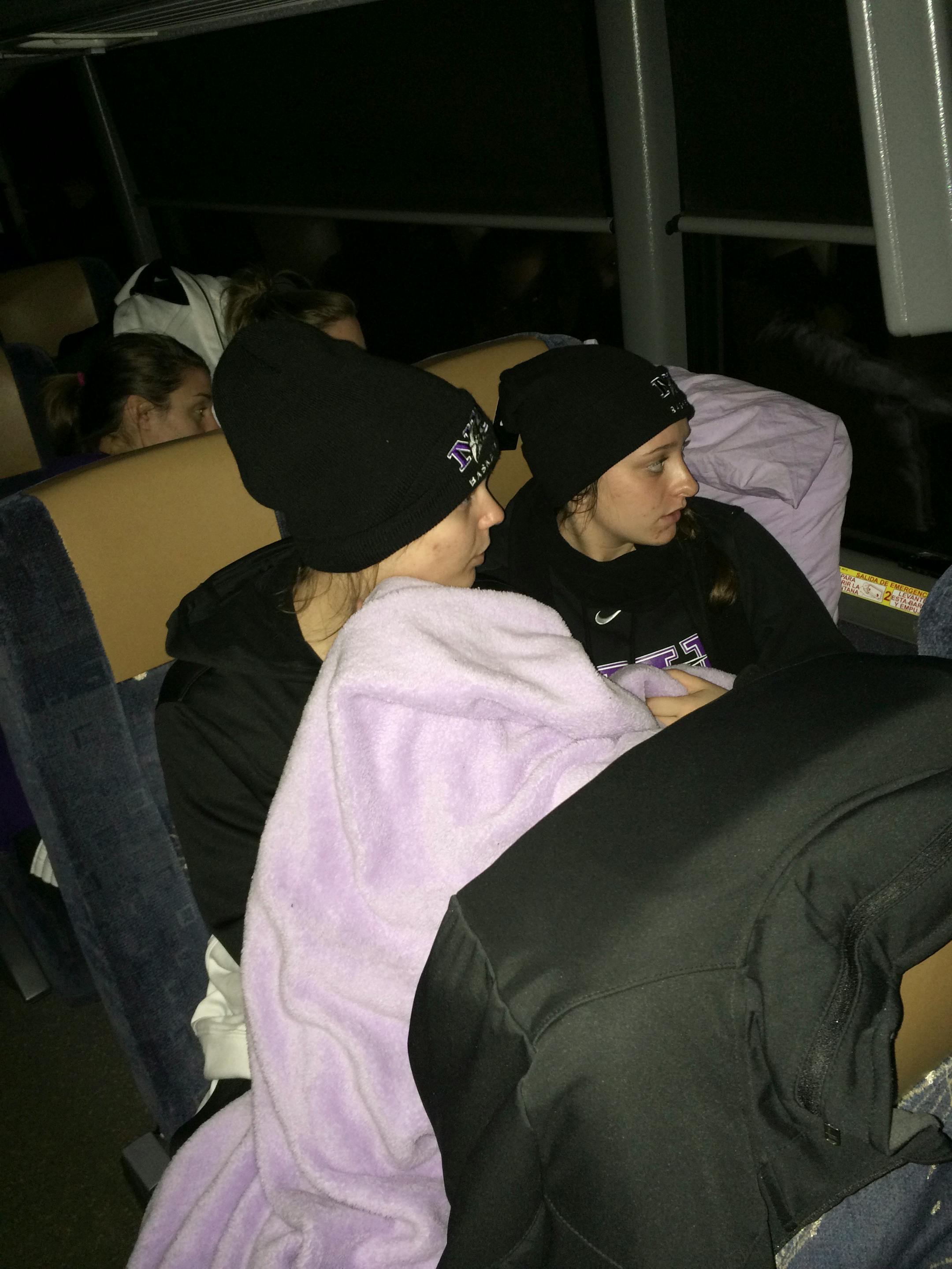 In this photo provided by Niagara's Tiffany Corselli, teammates Gabby Baldasare and Jamie Sherburne huddle under a blanket while stuck on a bus near Buffalo, N.Y., Tuesday, Nov. 18, 2014. The NCAA college basketball team has been stuck on the highway in its bus for nearly 24 hours because of a winter storm that dumped about 4 feet of snow around Buffalo. The team was coming back late Monday night from a loss at Pittsburgh when they were stranded. (AP Photo/Tiffany Corselli)