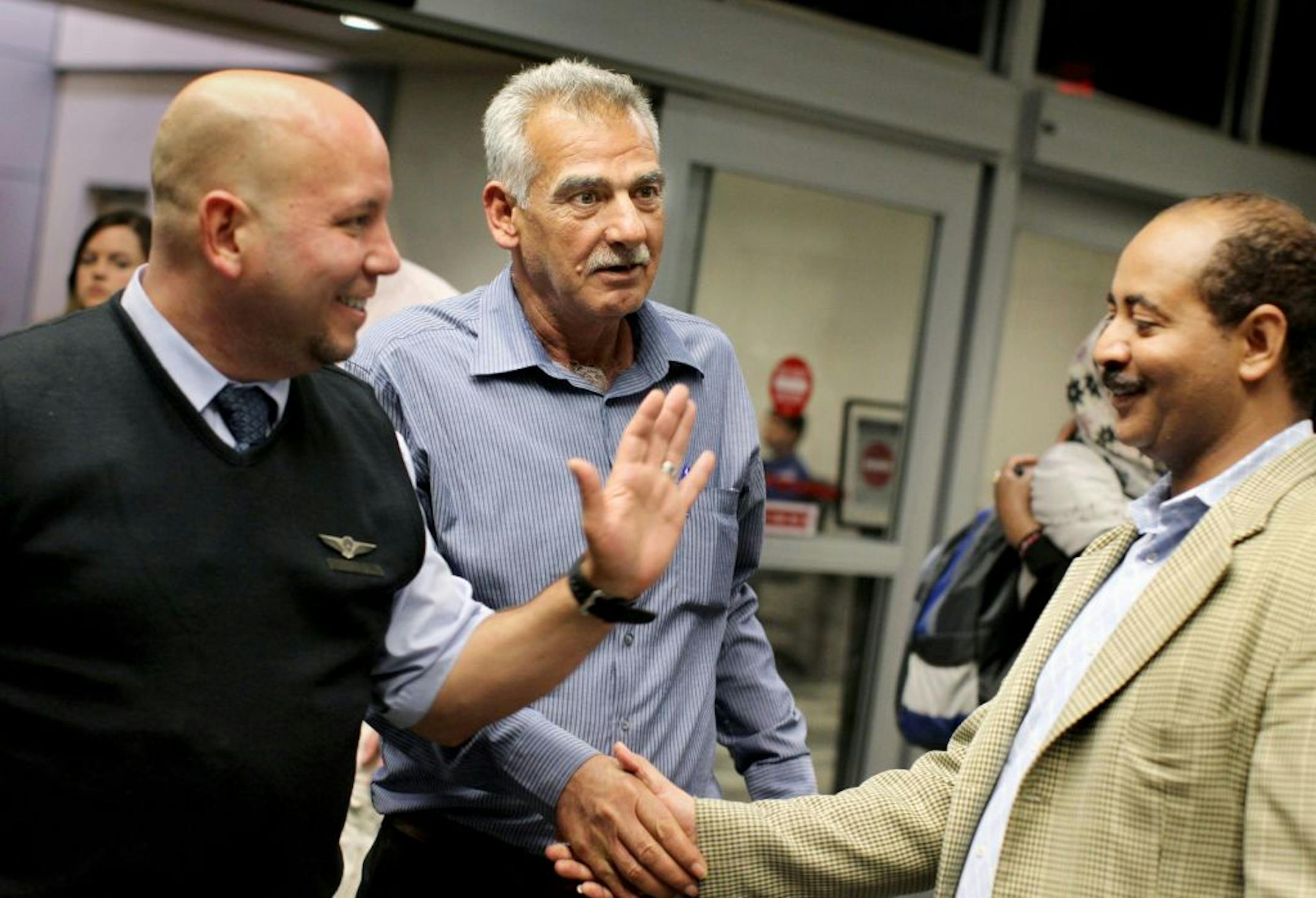 An airline employee, left, brings Iraq refugee Kareem Al Jaber, center, to meet Mesfin Tsegay, case manager with the International Institute of Minnesota, in the baggage claim area at Minneapolis St. Paul International Airport May 24, 2012. Al Jaber had just arrived from Jordan, via Chicago. He came alone and has no family in the U.S.