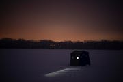 An angler fished inside a portable ice fishing shelter on Cedar Lake in Minneapolis in 2021.