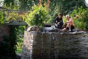 Yee Lee, left, and her husband Bryan Johnsen pose for a portrait in the retaining wall feature with a 6-foot waterfall, spiral staircase and bridge th