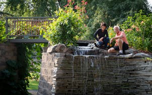 Yee Lee, left, and her husband Bryan Johnsen pose for a portrait in the retaining wall feature with a 6-foot waterfall, spiral staircase and bridge th