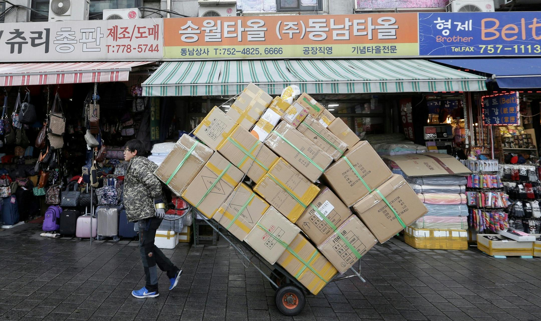 A worker carries a load of boxes at a shopping district in Seoul, South Korea, Friday, Jan. 13, 2017. South Korea's central bank lowered its forecast for the country's growth in 2017 due partly to the fallout from a massive influence-peddling scandal. (AP Photo/Ahn Young-joon) ORG XMIT: SEL109