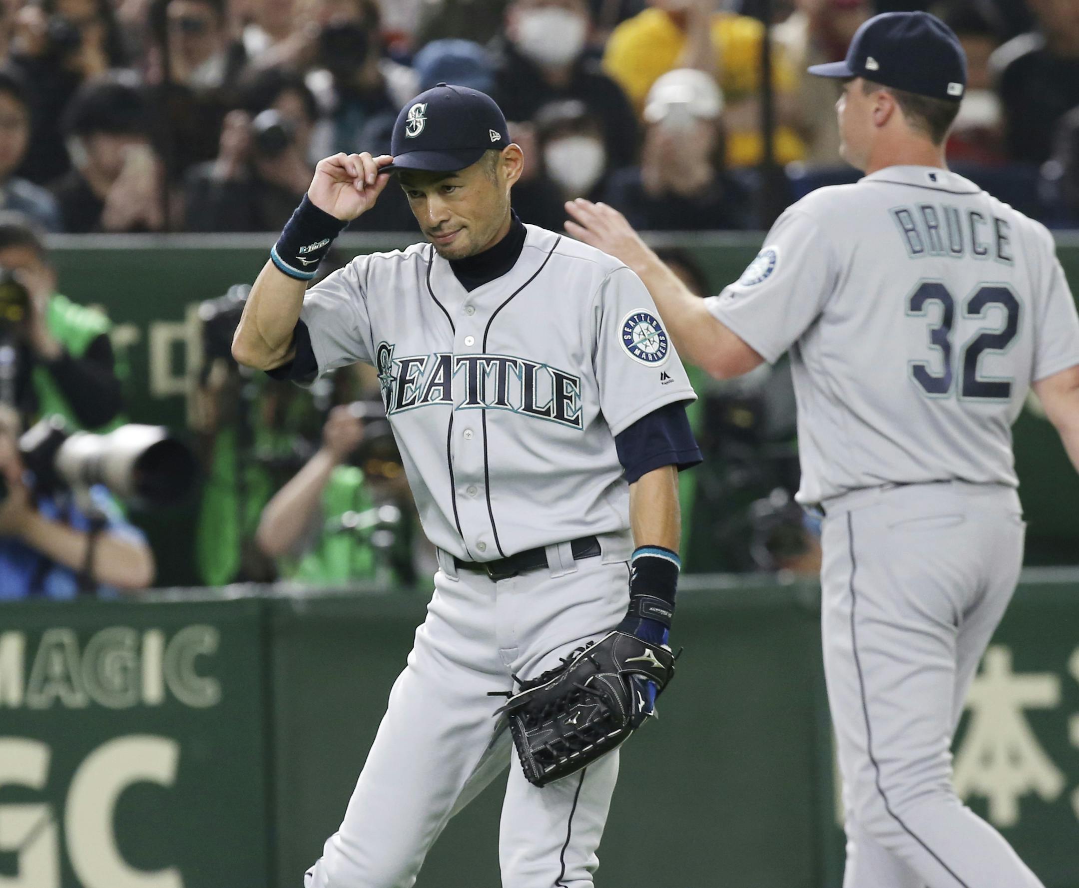 Seattle Mariners right fielder Ichiro Suzuki, left, gestures while leaving the field for defense substitution in the fourth inning of Game 1 of a Major League opening series baseball game against the Oakland Athletics at Tokyo Dome in Tokyo, Wednesday, March 20, 2019. (AP Photo/Koji Sasahara)
